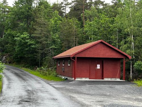 a red building on the side of a road at Cabin with sea, lake and hill view in Søndeled