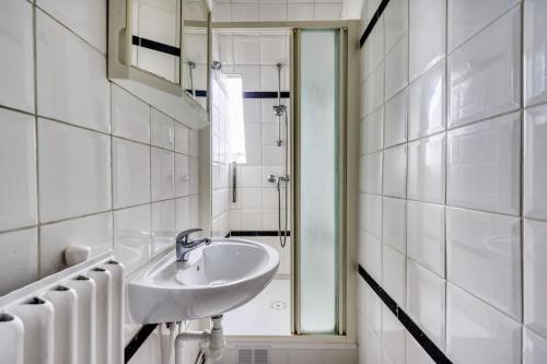une salle de bain blanche avec un lavabo et un miroir dans l'établissement 3-bedroom apart close to Roland Garros, à Paris