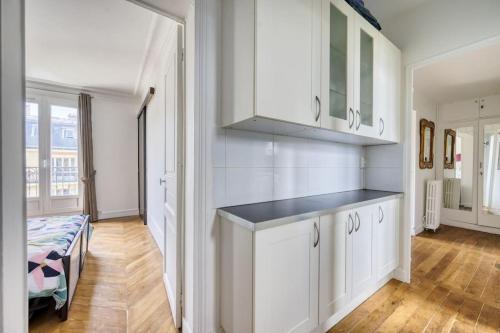une cuisine avec des armoires blanches et un lit dans une chambre dans l'établissement 3-bedroom apart close to Roland Garros, à Paris