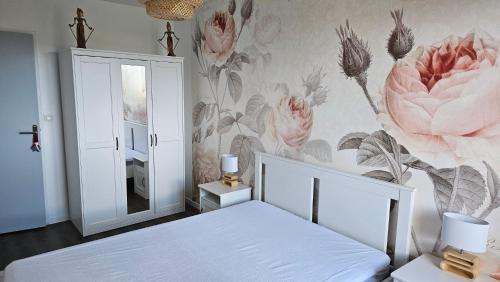 - une chambre avec un lit et un papier peint à fleurs dans l'établissement Appartement proche de la plage de Cabourg, à Cabourg