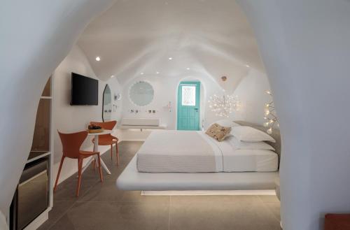 a white bedroom with a bed and a blue door at Naxos Cave Suites in Stelida