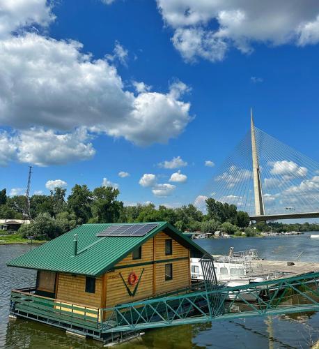 a house on a dock with a boat and a bridge at Splav Cilim House in Belgrade