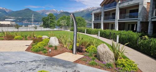 a garden in front of a building with mountains in the background at Dany Lodge Lago di Como in Colico