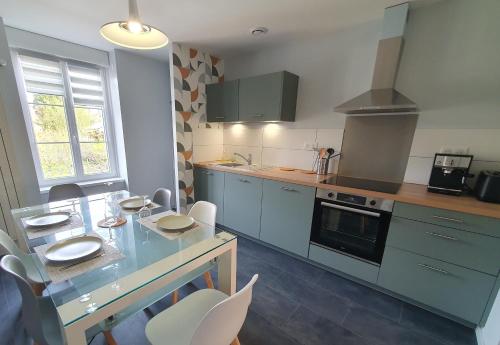 - une cuisine avec une table, des chaises et un comptoir dans l'établissement Gîte 4 étoiles le Doubs Cocon eurovélo6, à Abbenans