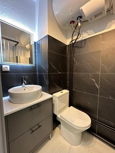 une salle de bain avec toilettes, lavabo et miroir dans l'établissement Studio vue mer avec parking Héliopolis village naturiste, au Cap d'Agde
