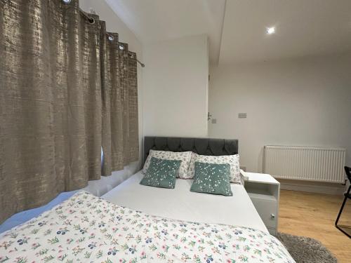 a bedroom with a bed with green and white pillows at 1st Studio Flat With full Private Toilet And Shower With its Own Kitchenette in Keedonwood Road Bromley A Fully Equipped Independent Studio Flat in Bromley