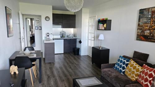un salon avec un canapé et une cuisine dans l'établissement Appartement proche de la plage de Cabourg, à Cabourg