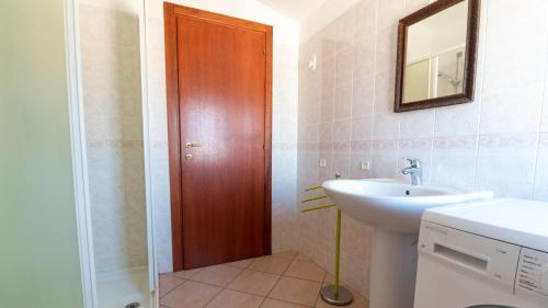 um banheiro com uma pia e uma porta de madeira em Casa Via Leopardi 124 em Càbras