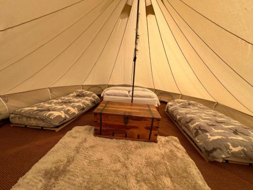 una camera con 2 letti e un tavolo in una tenda di Gwynfyd Bell Tent ad Abergavenny