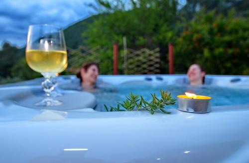 Una copa de vino y dos personas en una bañera. en Boka View by Roši en Tivat