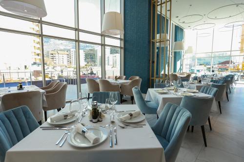 Apartments Lux sea view في بودفا: مطعم بطاولات بيضاء وكراسي ونوافذ