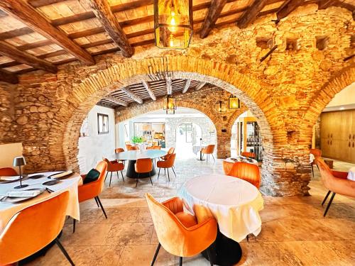 comedor con pared de piedra, mesas y sillas en AlliOli Boutique Hotel Spa en Castelló d'Empúries