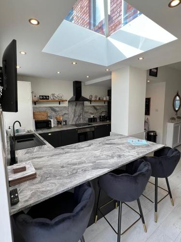 a kitchen with a large marble counter and two chairs at Beachside Suites - HOT TUB sleeps 10 in Blackpool