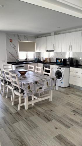 a white kitchen with a table and chairs in it at Paradise Breeze in Carvalhal