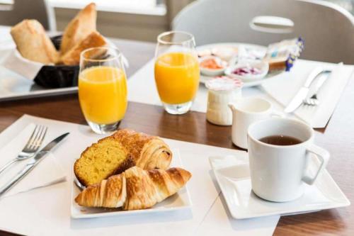 a table with a plate of bread and orange juice at Campanile NATURE - Bordeaux Sud Pessac in Pessac