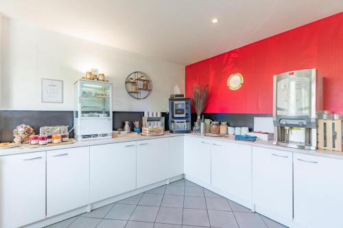 une cuisine avec des placards blancs et un mur rouge dans l'établissement Home, à Roubaix