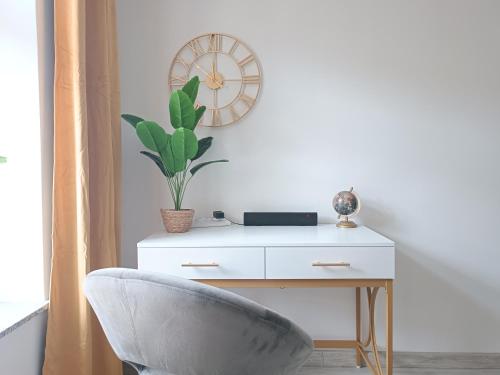 a desk with a chair and a clock on a wall at FILMAP-Charmant-Modern-Zentral-Balkon-Beamer-Spieletisch in Görlitz