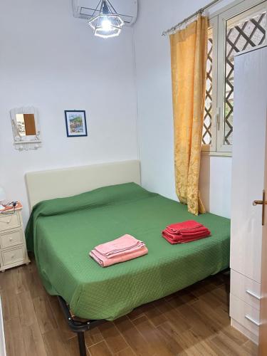 um quarto com uma cama verde com duas toalhas em House Cefalù 1915 em Lascari