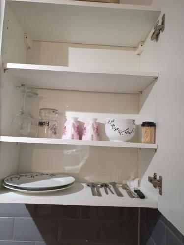 a shelf with dishes and utensils in a kitchen at Glorioushome in Basildon