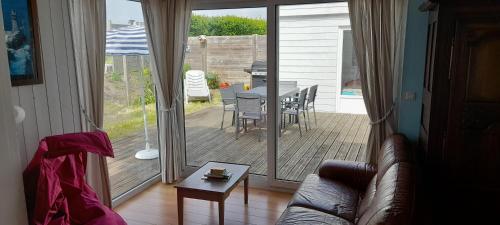 un salon avec un canapé et une terrasse avec une table dans l'établissement Skol Ar Louarn - Maison de vacances Ile-grande, à Pleumeur-Bodou