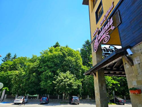 a sign for a restaurant with cars parked in a parking lot at Gardenia Park Hotel in Bansko