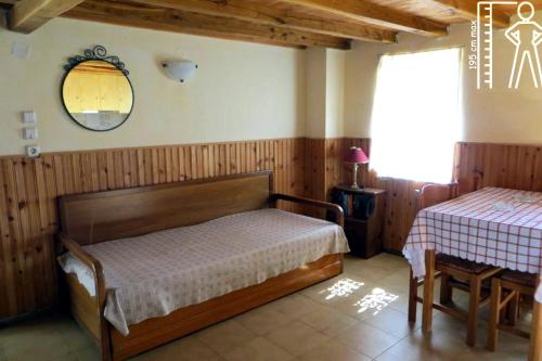 a bedroom with a bed and a table and a mirror at Tsorni Hill Cottage in Lefokastro