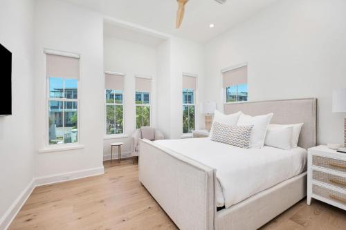 a white bedroom with a bed and windows at Del Mar in Seacrest