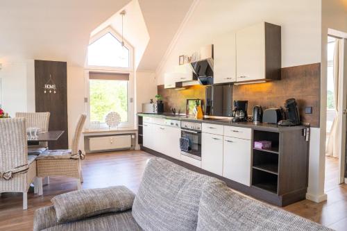 a kitchen with white cabinets and a living room at SmartFewo Loft Sauna Balkon Parkplatz in Bad Zwischenahn
