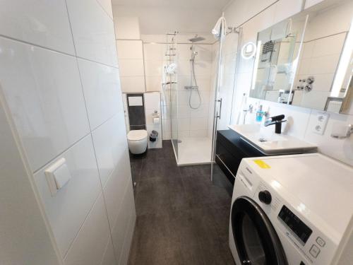 a bathroom with a sink and a washing machine at SmartFewo Loft Sauna Balkon Parkplatz in Bad Zwischenahn