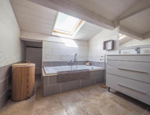 une grande salle de bains avec une grande baignoire et une fenêtre. dans l'établissement les gîtes du Montaigu, à Saint-Hippolyte-de-Montaigu