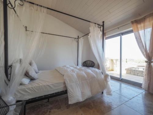 - une chambre avec un lit à baldaquin et une grande fenêtre dans l'établissement les gîtes du Montaigu, à Saint-Hippolyte-de-Montaigu