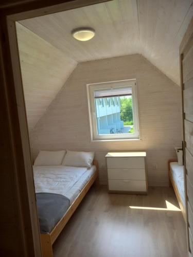 a small bedroom with a bed and a window at Domek Ga-Ba in Sarbinowo