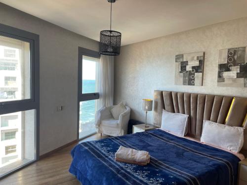 カサブランカにあるBelle-Vue sur Mer à Casa-Marina 9éme étageのベッドルーム1室(青い毛布と椅子付きのベッド1台付)
