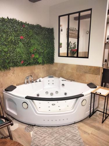 - une baignoire blanche dans une pièce avec une plante dans l'établissement Maison Prestige Le Donjon des Plaisirs Jacuzzi, à Montluel