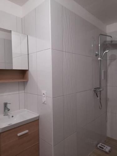 une salle de bain blanche avec une douche et un lavabo dans l'établissement Logement lumineux avec terrasse, à La Roche-sur-Yon
