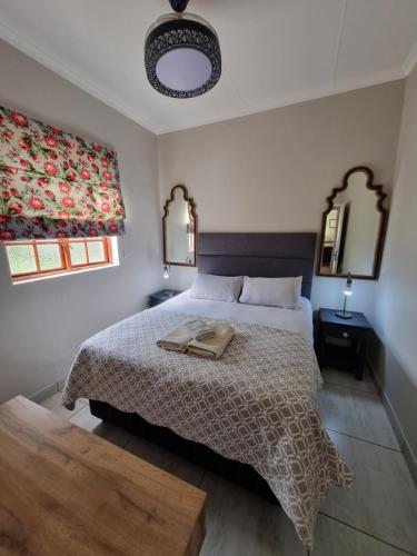 a bedroom with a large bed and two windows at KarooSjiek Self-catering in Adendorp