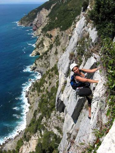 a man climbing up a cliff next to the ocean at La Mansarda sul Golfo in Portovenere