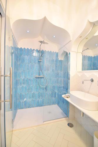 a blue tiled bathroom with a shower and a sink at Casa Mulini in Positano