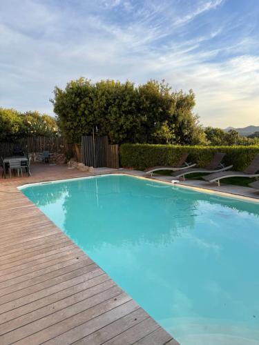 une grande piscine bleue avec une terrasse en bois dans l'établissement BENEDETU, à Porto-Vecchio