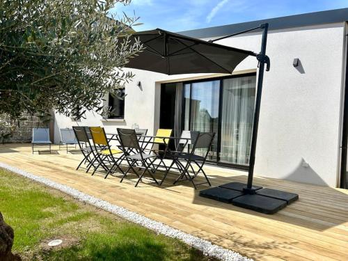a patio with chairs and an umbrella on a deck at Villa Molène jacuzzi et plage à 500 m in Tréveneuc