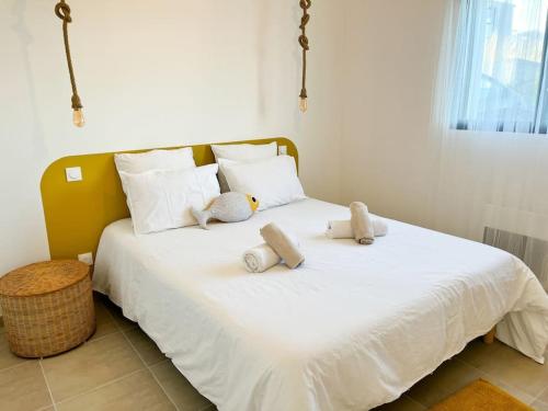 a white bed with stuffed animals on top of it at Villa Molène jacuzzi et plage à 500 m in Tréveneuc