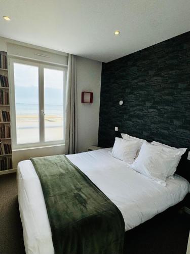 a bedroom with a large bed with a large window at Le Clos Normand in Saint-Aubin-sur-Mer