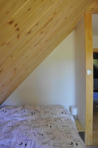 a bed in a room with a wooden ceiling at Cataleya Rajcza in Rajcza