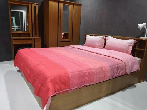 a bedroom with a large bed with a red blanket at Baan Sabaijai Resort in That Phanom