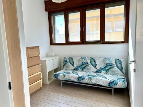 un divano sotto una finestra in una stanza di Donizetti Vacation Apartment a Porto Cesareo