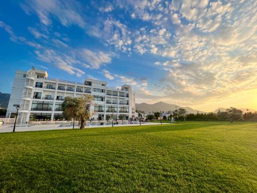 a white building with a grass field in front of it at Mc Palace Hotel Spa & Convention in Kyrenia