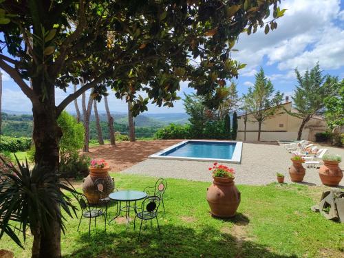 un jardín con mesa, sillas y piscina en Villa Il Fedino en San Casciano in Val di Pesa