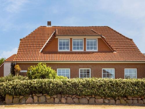a brown house with a red roof and a hedge at Giselas Ferienwohnung Ostsee in Holzstein in Oldenburg in Holstein