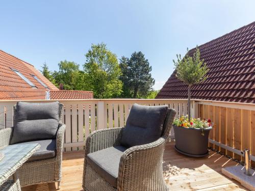 two wicker chairs on a deck with a fence at Giselas Ferienwohnung Ostsee in Holzstein in Oldenburg in Holstein