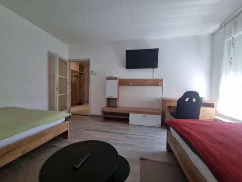a bedroom with two beds and a table and a tv at Studio apartman Milla in Karlovac